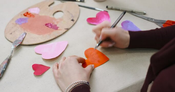 Signing handmade cards for Valentine's Day. Making crafted hearts, homemade gifts. Preparing for Valentine Day, close-up with unrecognizable woman