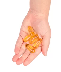 Raamstickers Lieve mosters Close up van visolie capsules op kinderen hand geïsoleerd op een witte achtergrond