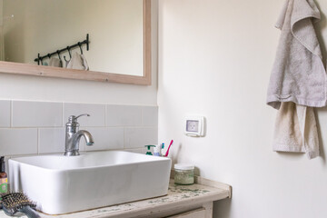 White sink on wood counter with a mirror hanging above it. Bathroom interior.