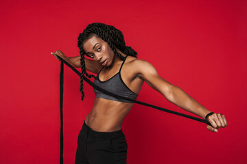 Young black sportswoman wearing bra posing with rope