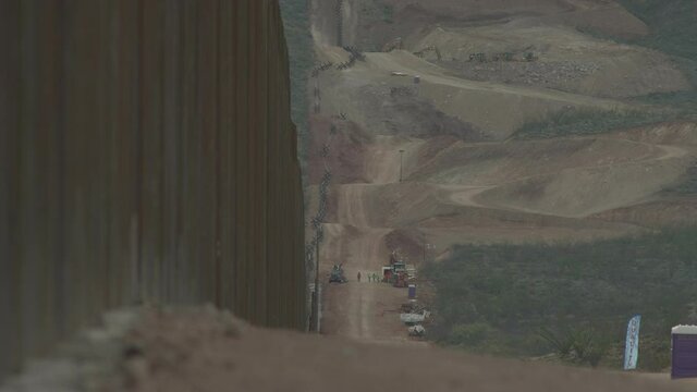 Construction workers on the border wall can be seen finishing the day and heading off the job site.