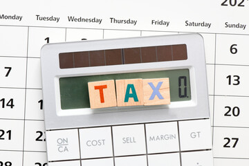TAX word arranged with wooden letters on the calculator screen.