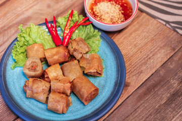 Deep fried spring rolls in blue plates with vegetables, chili and dipping sauce (Chinese food)