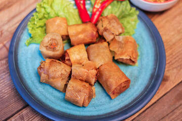 Deep fried spring rolls in blue plates with vegetables, chili and dipping sauce (Chinese food)