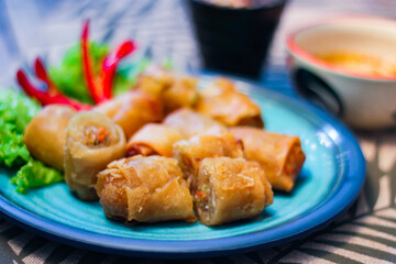 Deep fried spring rolls in blue plates with vegetables, chili and dipping sauce (Chinese food)
