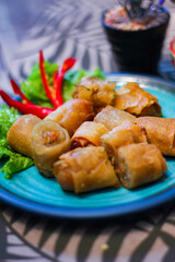 Deep fried spring rolls in blue plates with vegetables, chili and dipping sauce (Chinese food)