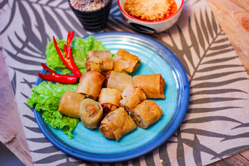 Deep fried spring rolls in blue plates with vegetables, chili and dipping sauce (Chinese food)