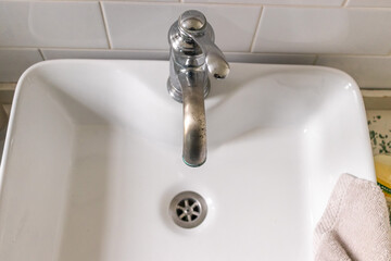 White sink on wood counter with a mirror hanging above it. Bathroom interior.