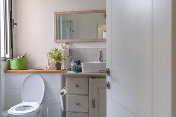 White sink on wood counter with a mirror hanging above it. Bathroom interior.