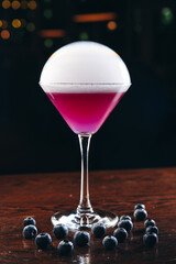 Smoking martini glass with purple drink. Cocktail with blueberries 