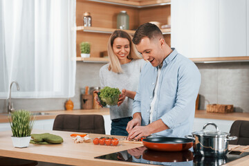 Man standing by the table. Couple preparing food at home on the modern kitchen