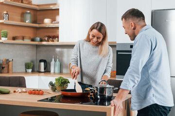 Delicious dinner. Couple preparing food at home on the modern kitchen