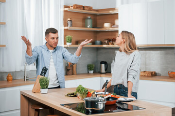 Screaming and arguing with each other. Couple preparing food at home on the modern kitchen
