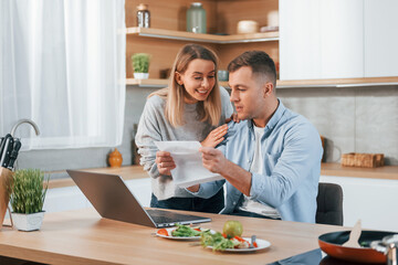 Using internet. Couple preparing food at home on the modern kitchen