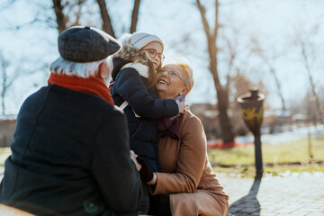 Grandma and grandpa enjoy with their sweet granddaughter on a sunny winter day.