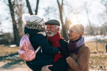 Grandma and grandpa enjoy with their sweet granddaughter on a sunny winter day.