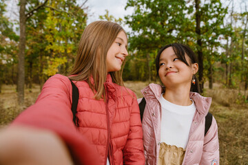 Fototapeta premium Multiracial teenagers smiling and taking selfie photo during hiking