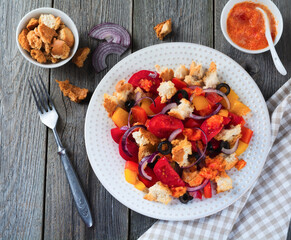 Salad with peppers, tomatoes, onions, olives and croutons with sousomna old wooden background. Selective focus.