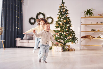 Running together. Little brother and sister is at christmas decorated room