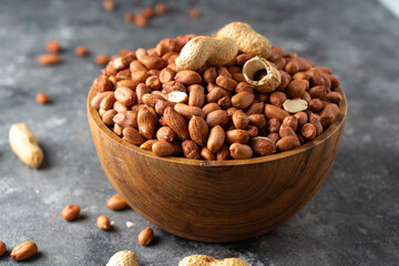 Raw Peanuts in wooden bowl on natural gray rustic desk.