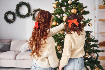 Decorating tree. Mother with her little daughter is at home
