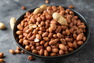 Raw Peanuts in wooden bowl on natural gray rustic desk.