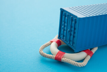 Blue container on lifebuoy blue background with copy space. Marine cargo shipment or freight...