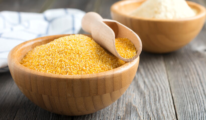 Raw corn grits polenta in a bamboo bowl on the old wooden background. Selective focus