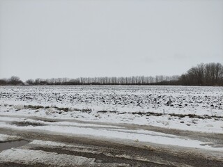 Agricultural field in the snow and dirty country road