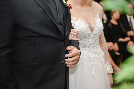 Shot of a mature man in a black suit walking his daughter bride in white lace gown down the aisle while her groom waits at the wedding altar Cropped photo