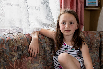 Portrait of girl (4-5) sitting on sofa in caravan