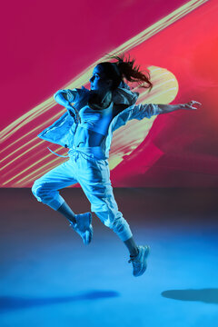 Woman Dancing With Raised Hands In Colorful Studio