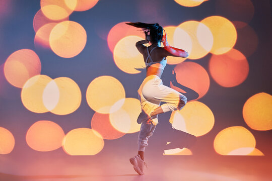 Energetic woman dancing on one leg and listening to music