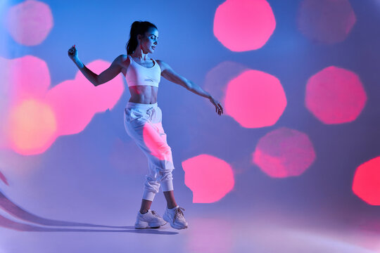 Graceful woman in white studio with bright lights