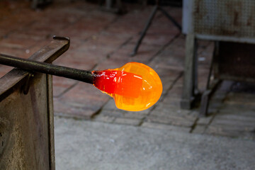 Glass blower forming beautiful piece of glass. A glass crafter is burning and blowing an art piece.