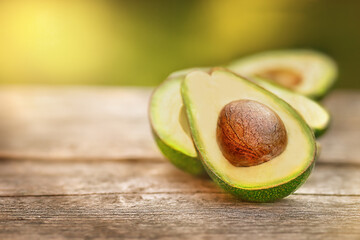 Avocado halves lie on the wooden surface of the table. Bright yellow background.