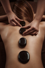 Woman getting spa treatment. Hot stone therapy. Top view. 