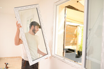 handsome young professional man installing and replacing a new home window in client house for improvement energy saving efficiency isolation