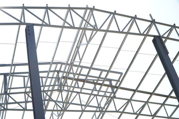 Fototapeta premium Structure of steel roof frame for building construction on sky background.