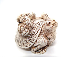 figurine of a turtle with three frogs on a shell on a white background.