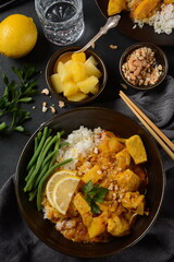 A Chicken Massaman Curry in black bowl at dark background. Massaman Curry is Thai Indian best dish with chicken meat, potato, onion and many spices is influenced by Malay and Thai Muslim cultures.