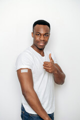 Healthcare concept. Smiling African American man with a band-aid on his shoulder after receiving a...