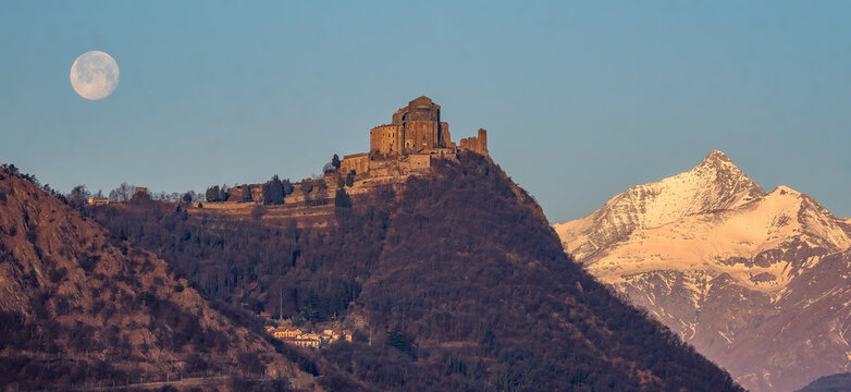 The Sacra di San Michele (Saint Michael Abbey) , the symbol of the Italian region of Piedmont, In the background the mountains of the Val di Susa with full moon. 