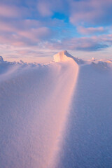 Snowdrift waves in sunset light, purple evening light at winter with a lot of snow, vertical image