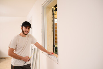 handsome young professional man installing and replacing a new home window in client house for improvement energy saving efficiency isolation