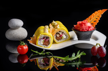 Sushi rolls on a white plate on a black background with reflection. Dinner atmosphere.