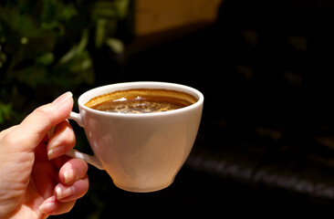 Closeup of woman's Hand Holding a Cup of Aromatic Hot Coffee 