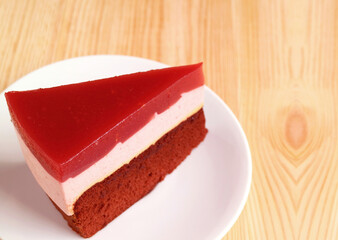 A Slice of Raspberry Mousse with Chocolate Layer Cake on Wooden Backdrop
