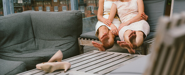 Two young lesbians are sitting at a roof of a hotel.