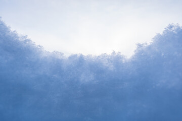 Fluffy snow against the sky, on a frosty winter evening. Copy space. Abstract background. Bottom view.